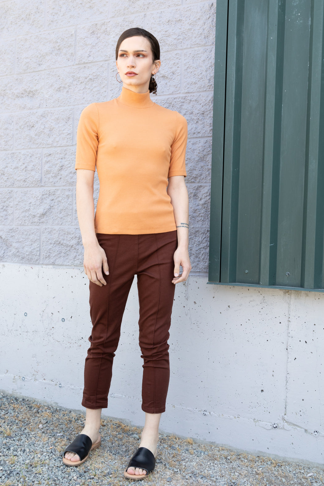 Photo of a sherbet orange, organic cotton tee in a thick rib with sleeves just above the elbow and a mock neck. Incredibly stretchy, it skims the body and holds its shape.