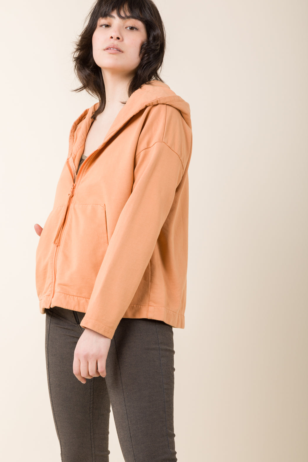 Our Square Pegs is a 100% organic cotton hoodie with a boxy fit, a zip-front, and dual patch pockets. The abbreviated length, hits just below the waist and is complete with a drop shoulder and narrow sleeves. 